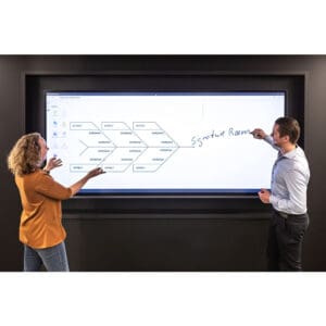 Two people discussing diagram on large screen.
