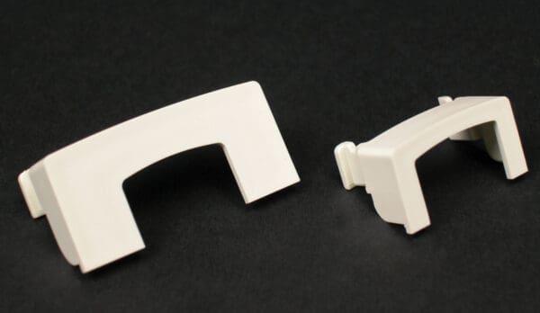 Here's an 8-word alt tag for the image: Two off-white plastic corner pieces for molding.