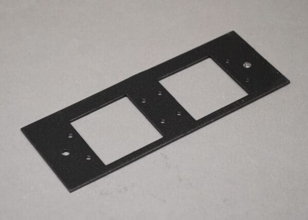 Black metal plate with two cutouts.